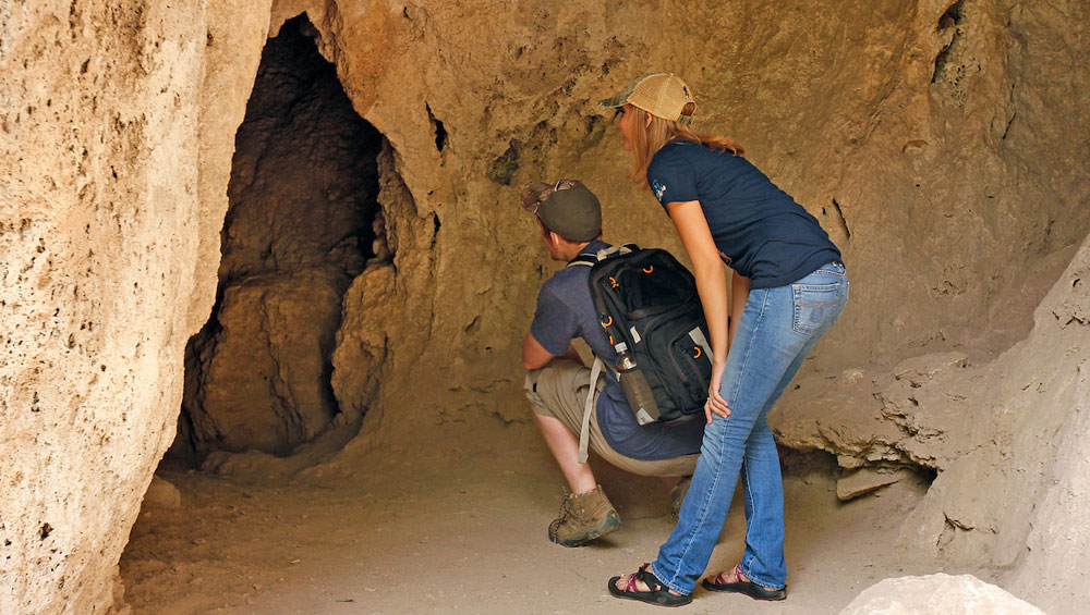 Caves You Can Visit A pair of visitors examine the caves near the falls.